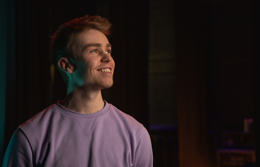A man wearing a lilac jumper and smiling broadly